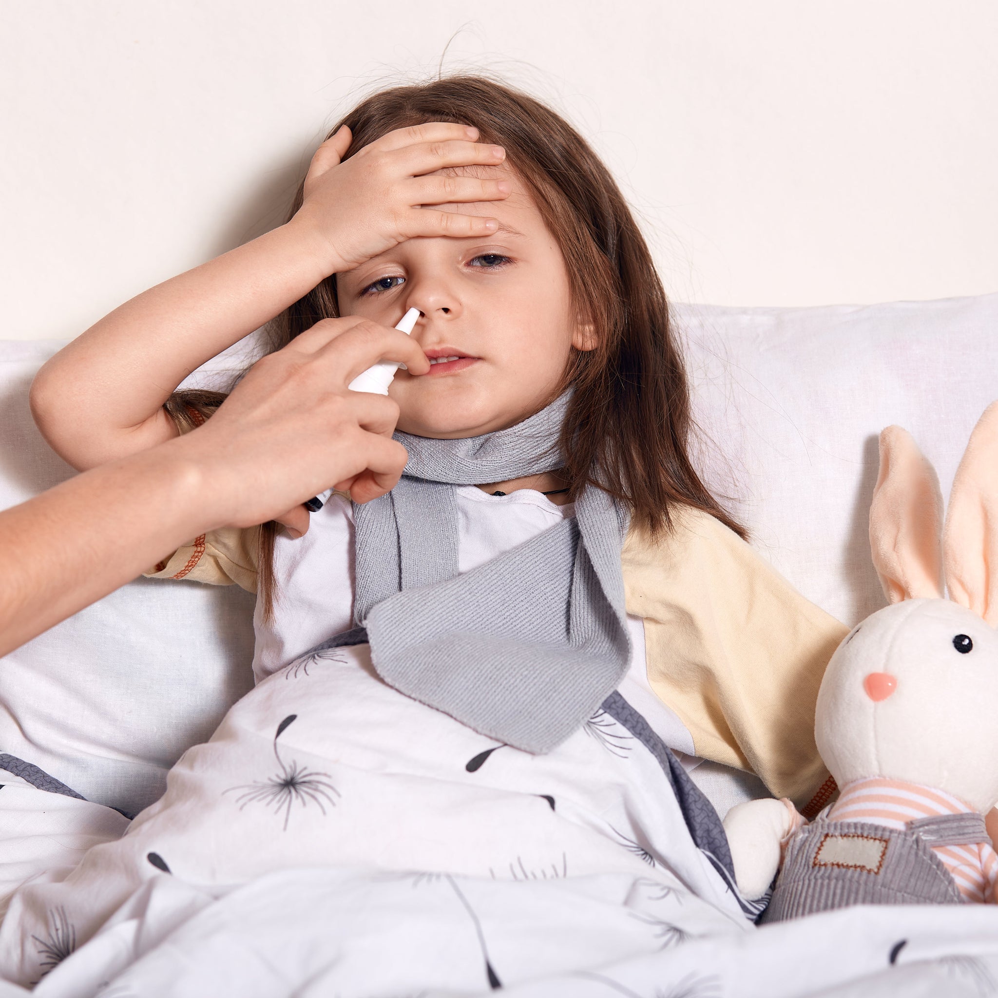 A sick girl with her stuffed rabbit, possibly allergic to her pet rabbit