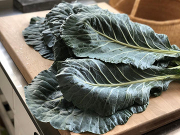 A bunch of fresh collard greens lying on a table.